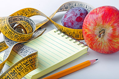 notepad, pencil, tape measure and fruit