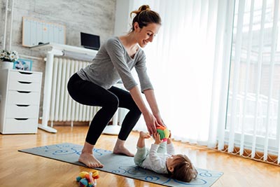 woman doing squats at home with baby